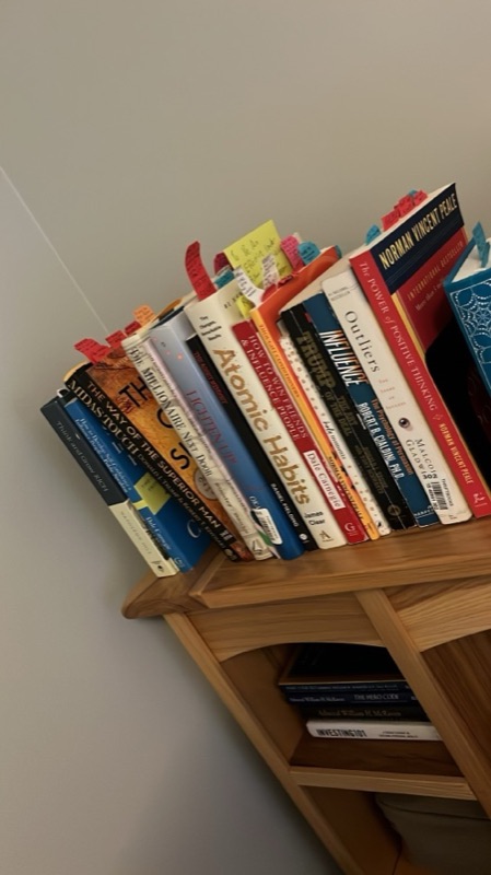 A shelf of business books full of sticky notes