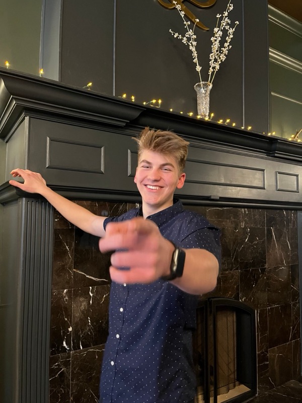 Pointing at the camera by the fireplace